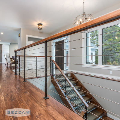 Modern interior cable railing with 232 series through-post fittings on square metal posts and wooden handrail.