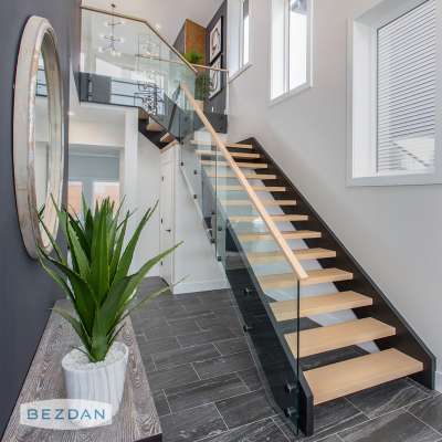 Modern staircase with frameless glass railing using black stainless steel round single standoffs 6102, 6212.