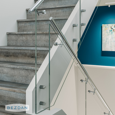 Glass staircase railing with stainless standoff 6110, adjustable saddle 0738, and round tube 9010 in a modern interior.