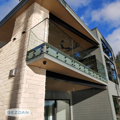 Exterior glass balcony railing with black stainless standoffs 6102 on a modern multi-level home.