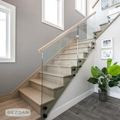 Interior glass railing with stainless standoffs 6102 and 6212, featuring round black fittings on a modern wood staircase.