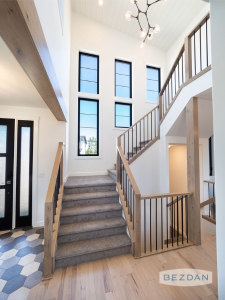 Contemporary entryway with simple square spindles and wood handrails.