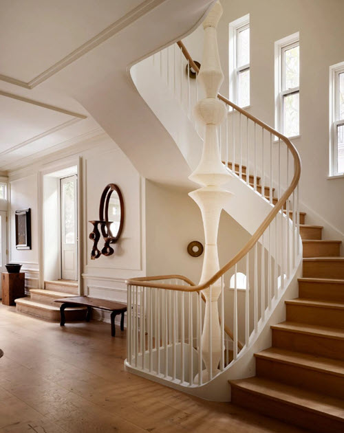 A staircase with curved wooden handrails on white steel tube balusters