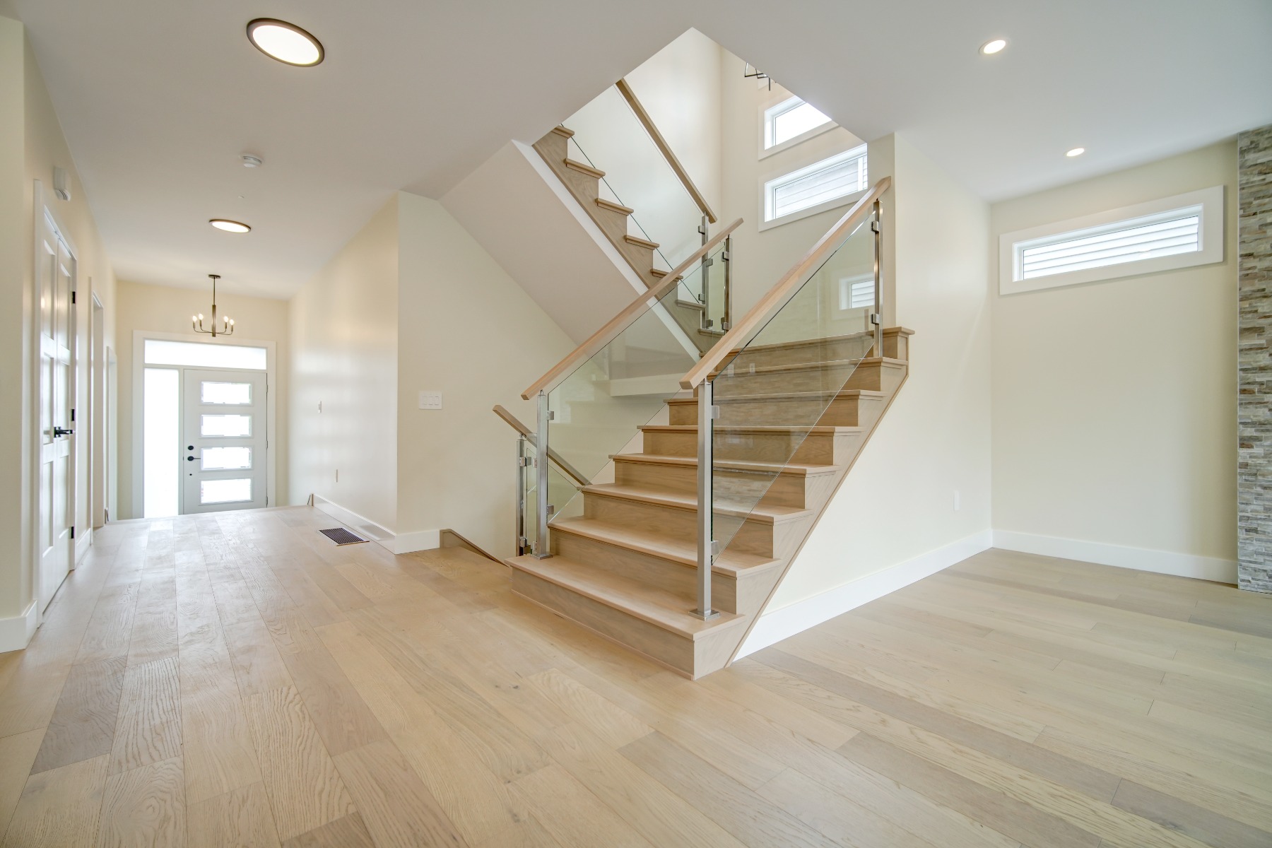 a bright modern space with wood and glass staircase railing