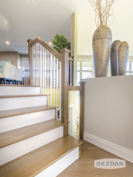 Warm white spindles with a subtle gloss finish, installed in a wood handrail for a clean, modern look.