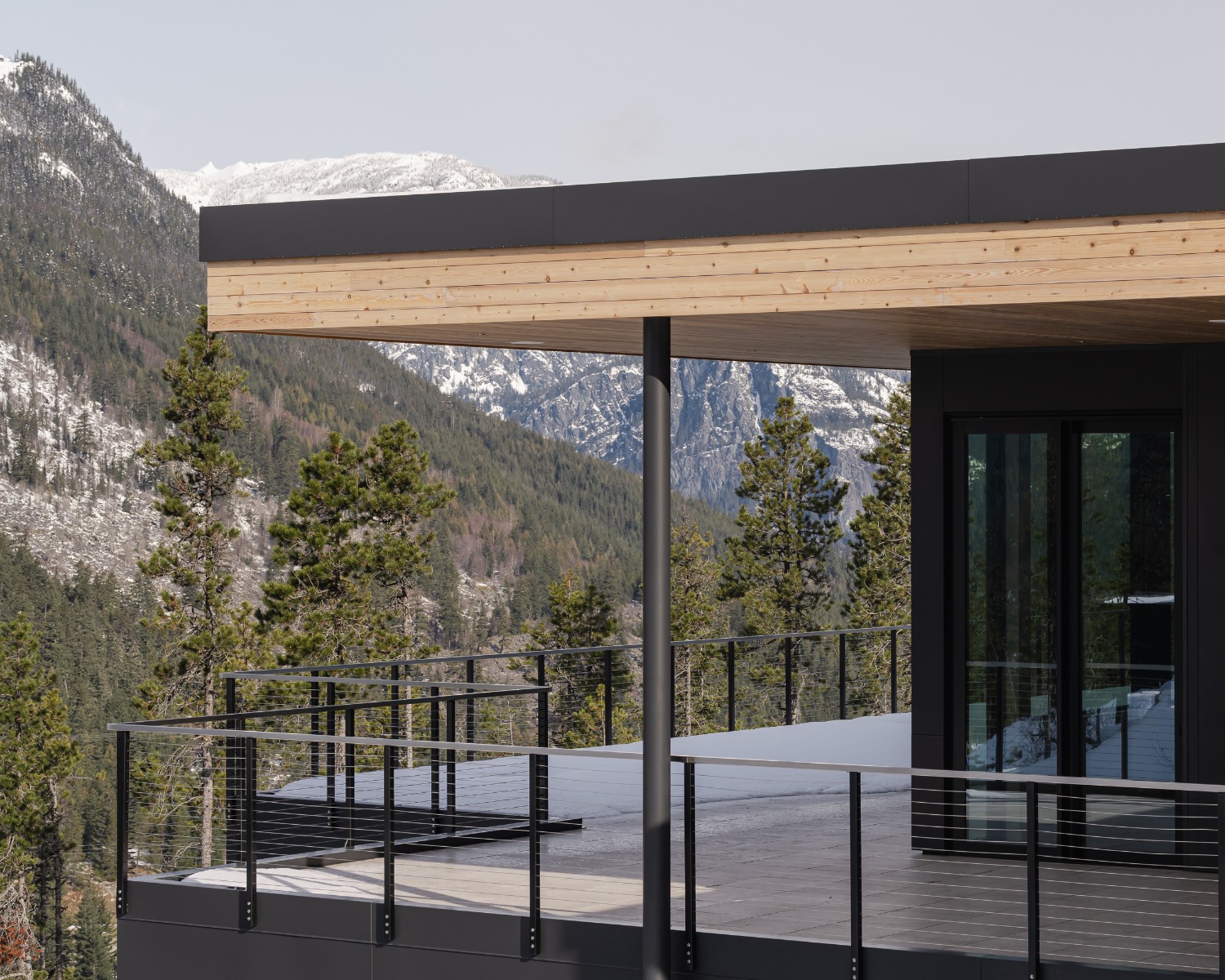 Modern mountain home deck featuring a sleek black stainless steel cable railing with black PVD-finished stainless steel posts and horizontal cables, showcasing a durable black stainless steel railing solution designed to preserve views in contemporary exterior architecture.